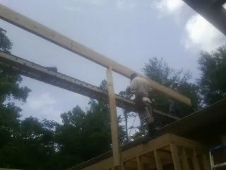 Carpenter setting a ridge beam over a new addition frame — Ice Dam Removal by Roofing Brothers in Smithmill