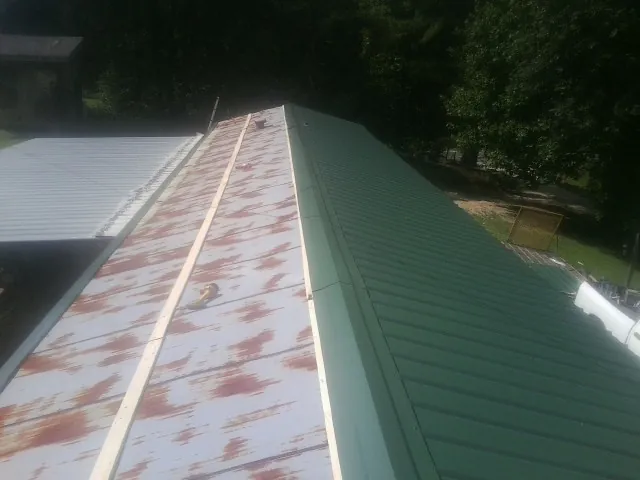 Old rusted panels beside newly installed green metal roofing — Wind Damage Roof Repair by Roofing Brothers in Smithmill