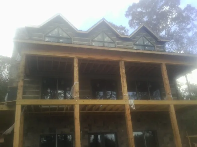 Dormers and porch framing on a large log home under construction — Roof Coating work by our crew in Smithmill