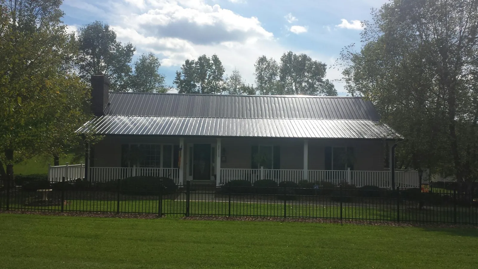 Gray metal roof on a brick ranch with a full width front porch — Gutter Guard Installation work by our crew in Smithmill