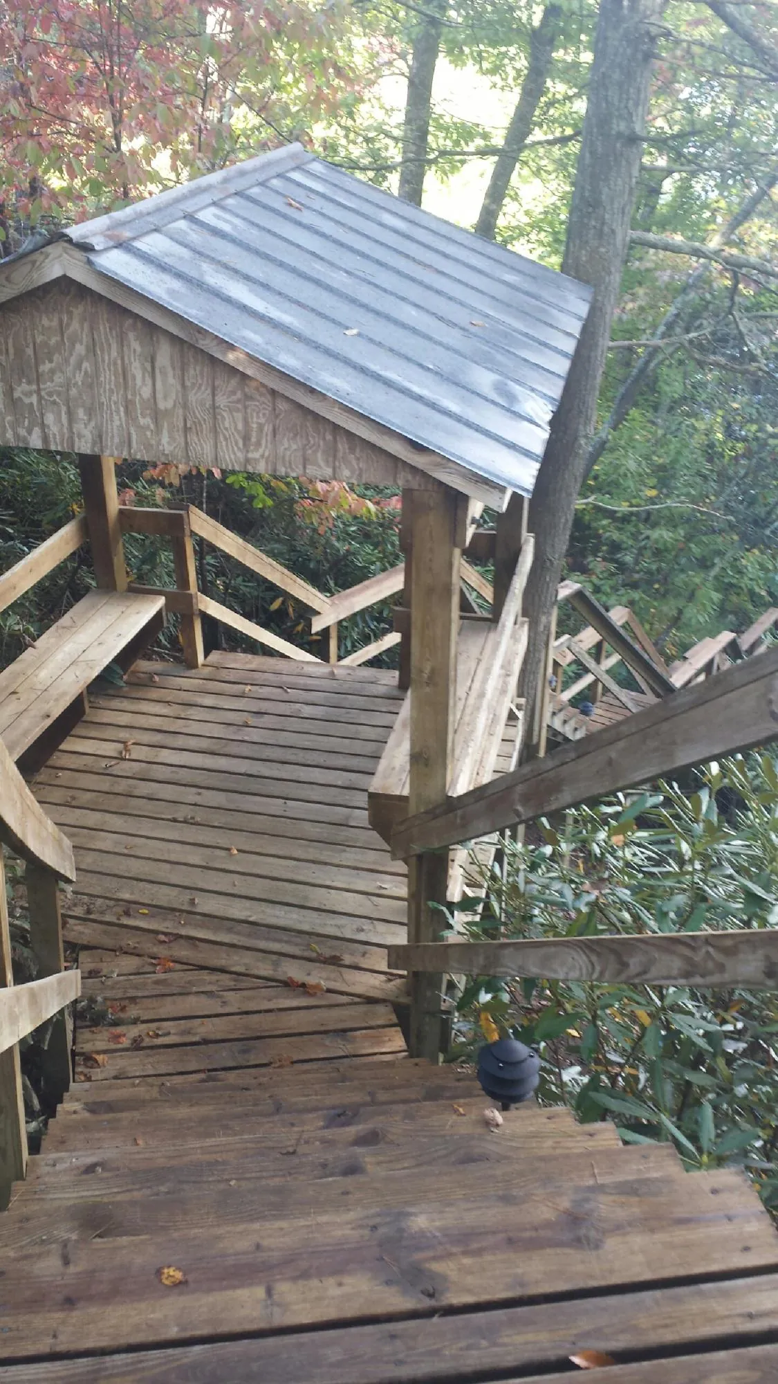 Metal roofed shelter over wooden steps on a wooded walkway — Skylight Repair & Installation work by our crew in Smithmill