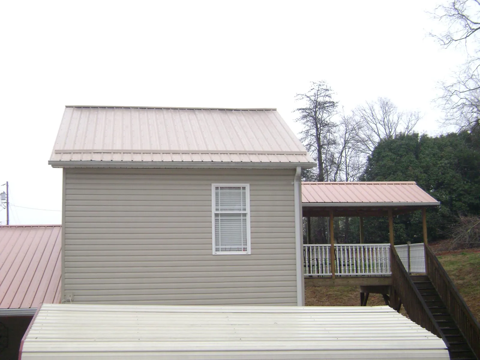 Tan metal roofs on a two story addition and attached porch, from a Roof Replacement job in Smithmill